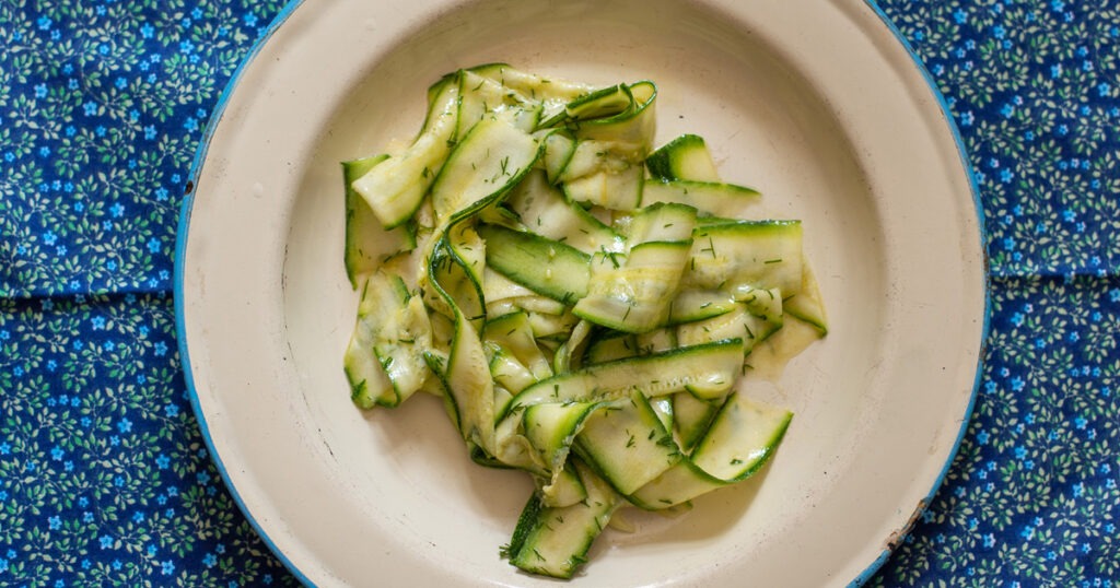 Plate of pickled courgettes on blue tablecloth