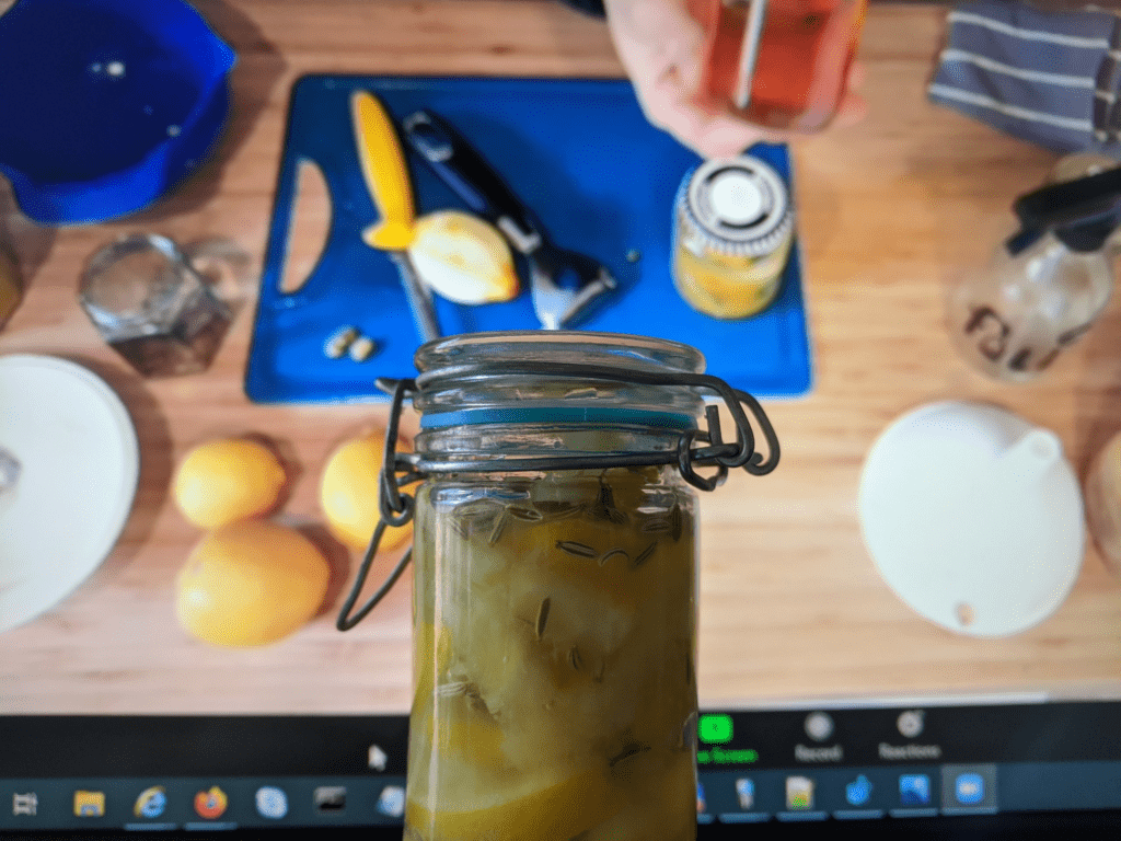 A jar of homemade lemon cleaning spray, held up against a virtual tutorial.